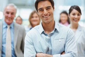 Confident smiling business man with his team at the back