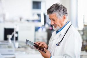 Senior doctor using his tablet computer at work