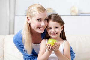 Smiley mummy with her keeping sweet green apple daughter