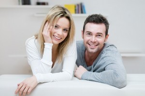 Young happy couple smiling together at camera in their home