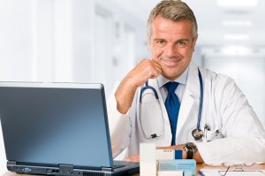 Happy satisfied mature doctor working and looking at camera in his modern clinic office