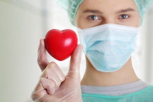 Male surgeon looking at camera at hospital and holding red heart,   close up shot