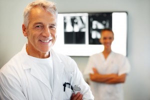 Portrait of smiling male doctor in clinic with a female nurse in background