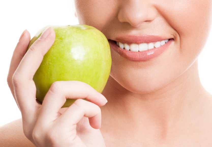 closeup of the face of a woman holding a green apple,   isolated against white background