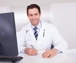Smiling Medical Doctor With Stethoscope Sitting At A Desk