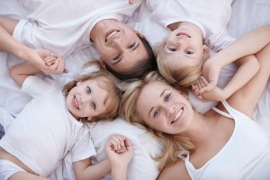 Smiling family lie on a white bed