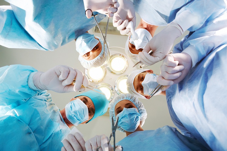 Below view of surgeons holding medical instruments in hands and looking at patient