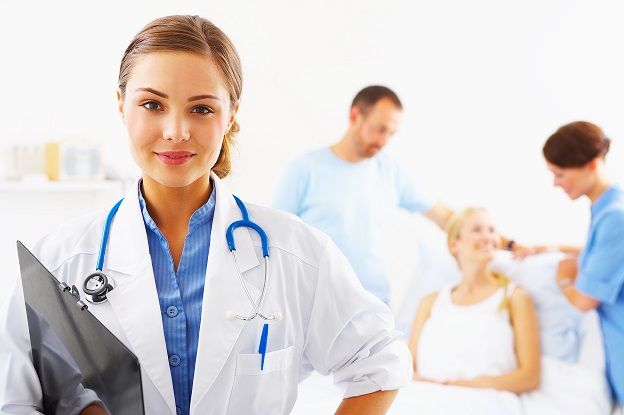 Portrait of a doctor with two of her co-workers talking with a patient in the background