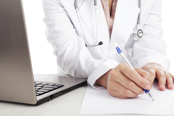Doctor woman with stethoscope and laptop writing on the paper