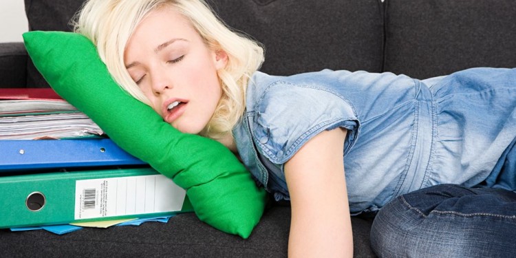 Mujer-joven-perezosa-dormida-en-un-sillon-negro-apoyando-su-cabeza-en-un-cojin-verde-donde-debajo-hay-un-archivador-y-varios-papeles-d