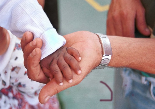La mano de un bebe subsahariano de 4 meses llegado en patera y la mano de Manuel  "Chispa", pescador de Tarifa y voluntario permanente para ayudar a los inmigrantes. Javier Bauluz