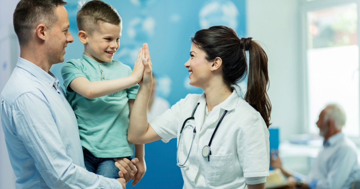 doctora feliz dando alta fie a un niño que vino con su padre al hospital
